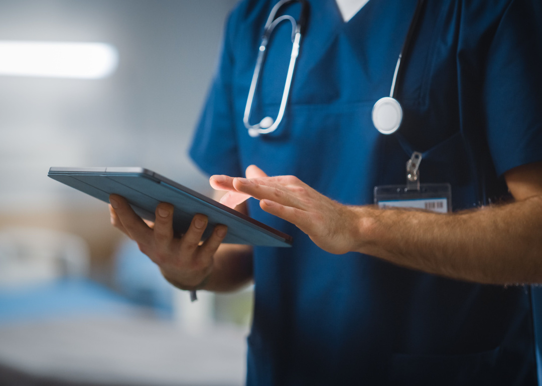Nurse using tablet in hospital ward.