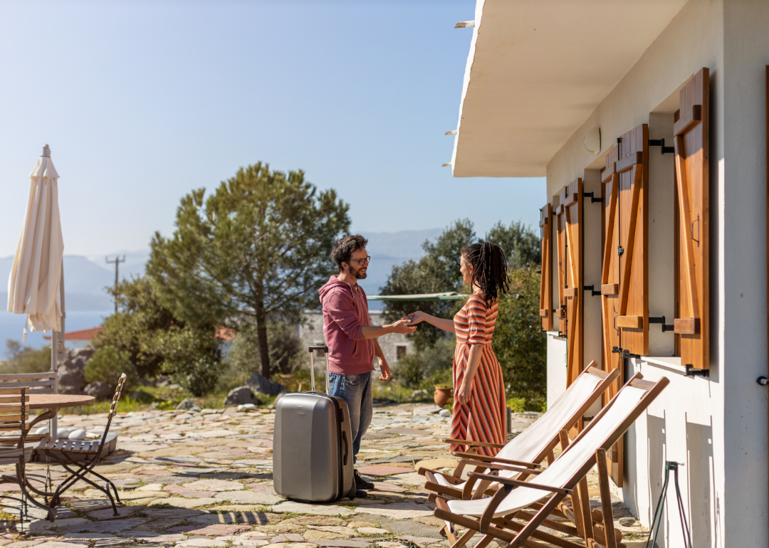 An Airbnb host hands over the keys to a guest in front of the property. 