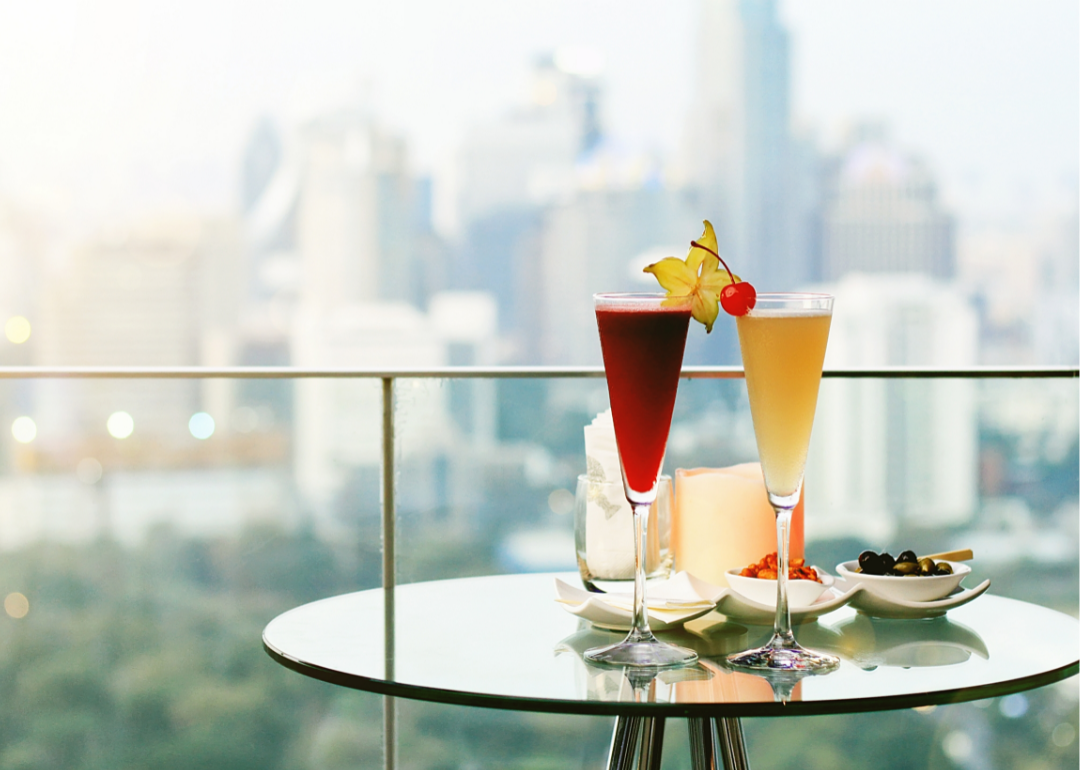 Two cocktails on a table on a rooftop bar in a city.