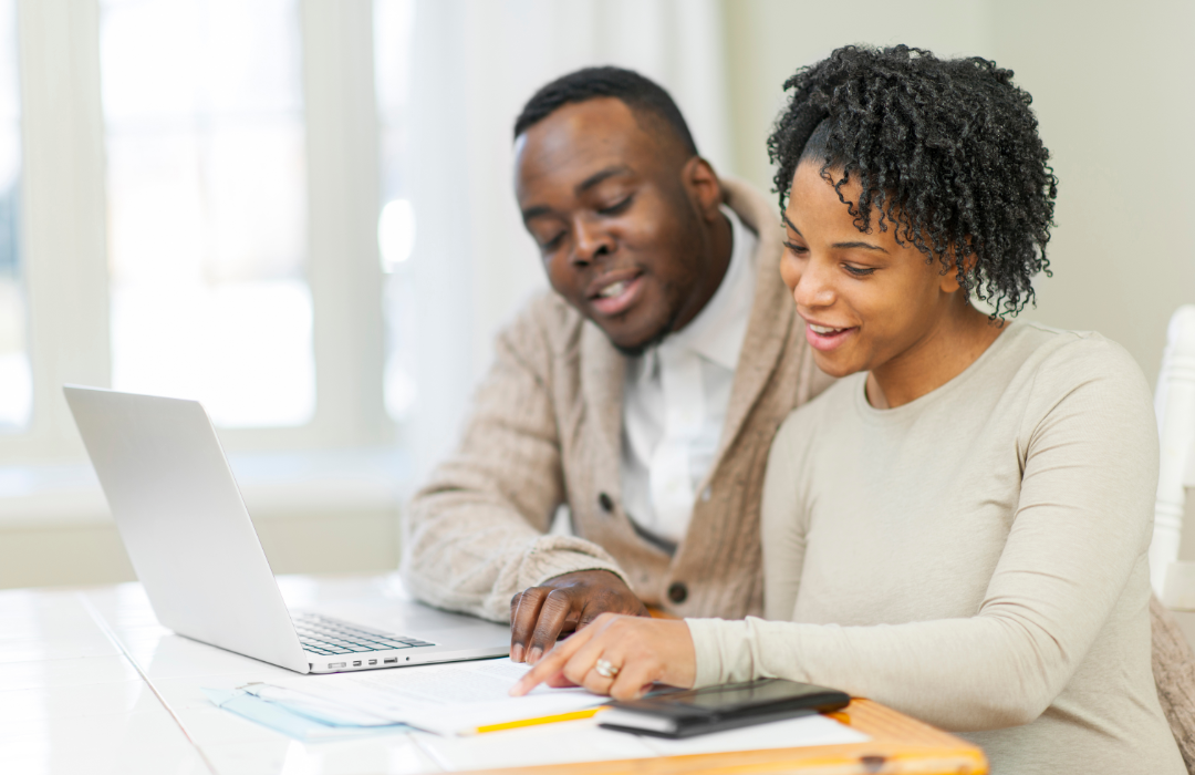 Couple looking at finances in front of laptop.
