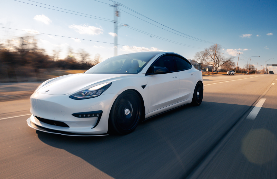 White Tesla driving on the road.