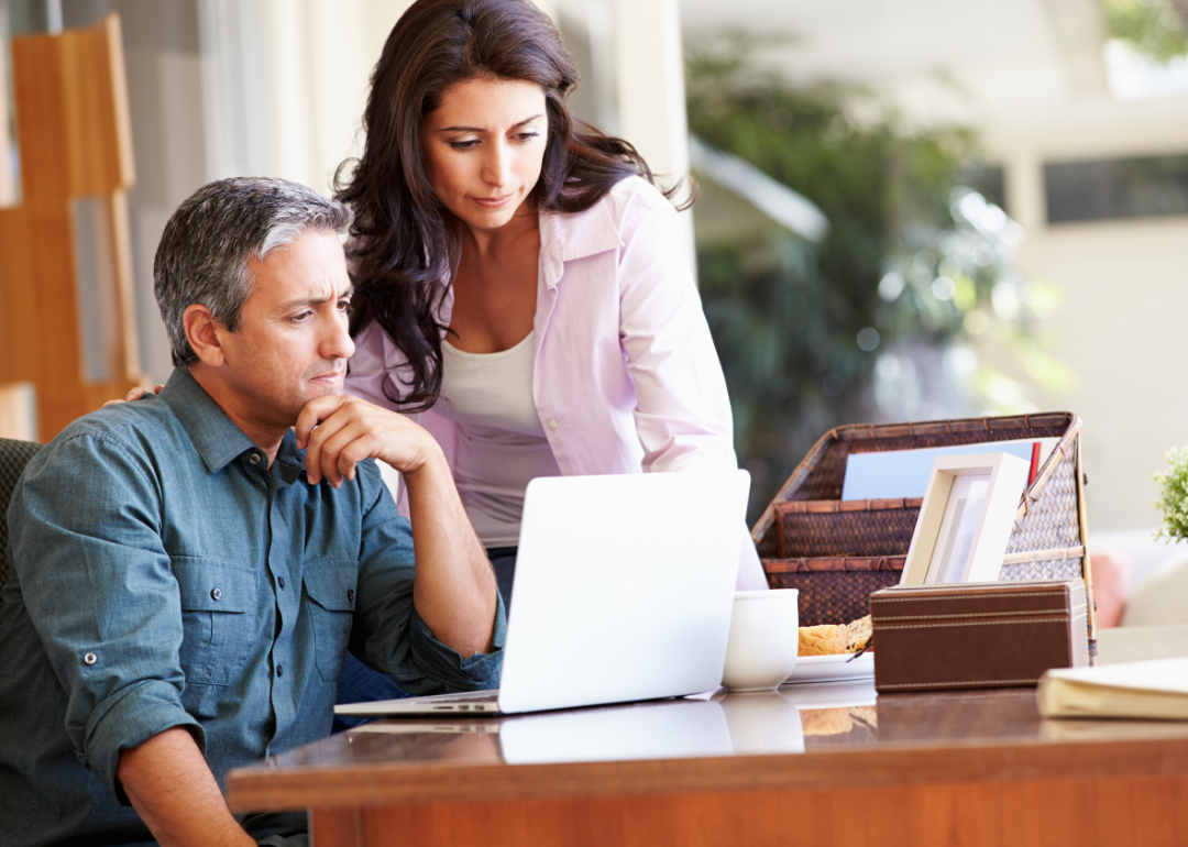 A concerned couple look at their laptop.