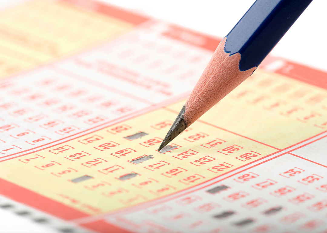 A person filling out a lottery ticket by hand.