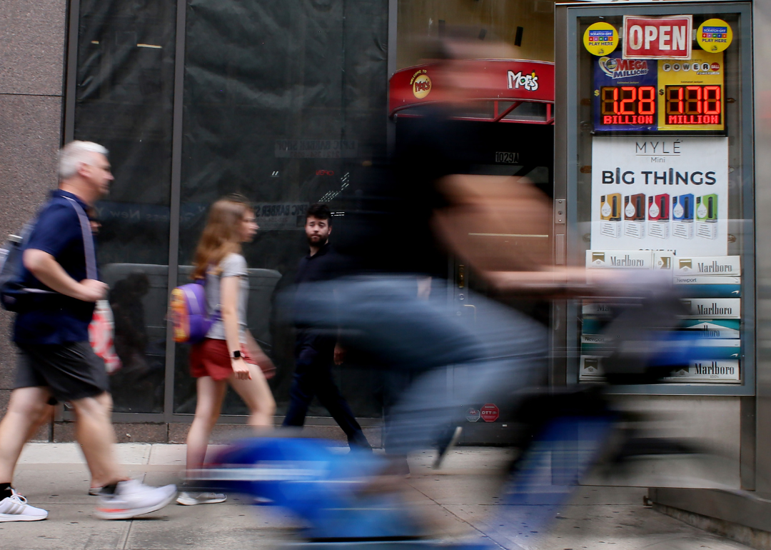 People walking by advertisements for the Mega Millions and Powerball lottery in New York City. 