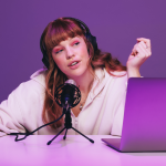 Podcaster recording an audio broadcast in neon purple light.