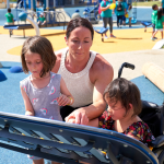 Woman and children at a universally accessible playground