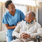 Nurse assisting a man in wheelchair.