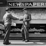 Man buying newspaper from vendor on sidewalk.