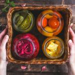 Glass jars of homemade pickled vegetables in box.