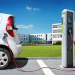 Electric car on charging spot in front of office buildings.