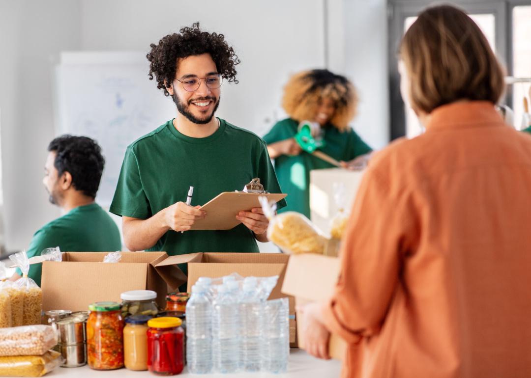 Volunteer with clipboard organizing donations.