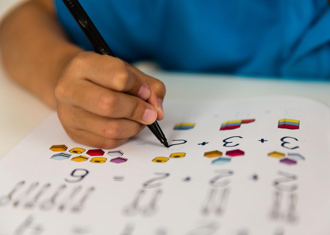 Child working on math assignment at desk.