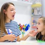 Preschooler practicing correct pronunciation with a speech therapist.