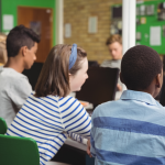 Students in a classroom listen to their teacher