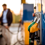A man pumping gas with green and yellow gas pumps in the foreground