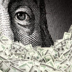 Close up of Benjamin Franklin portrait with hundred dollar bills in the foreground