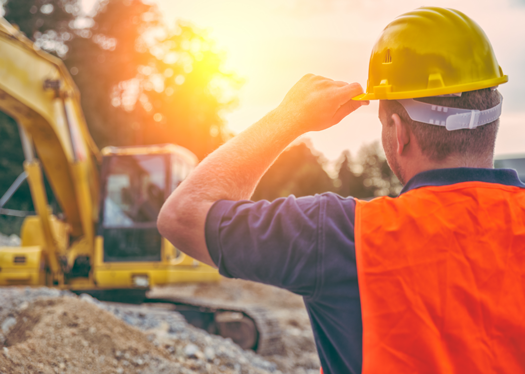 A construction worker looks into the sunset at a work site.