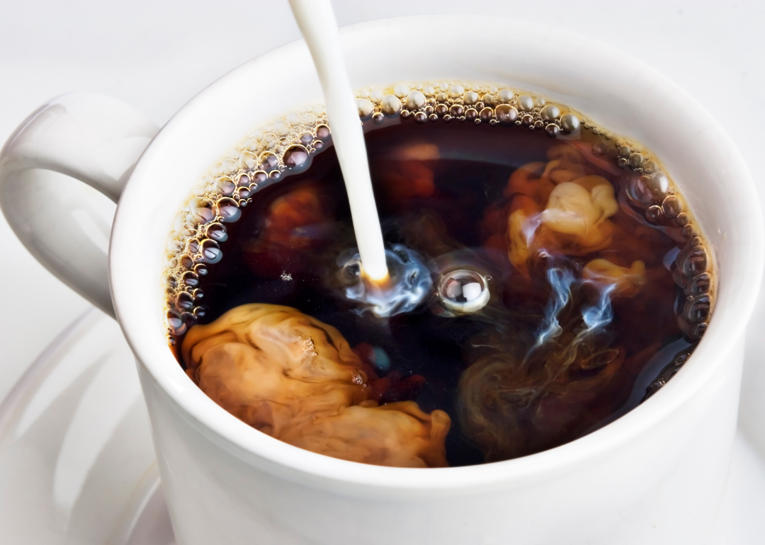 Milk being poured into a cup of coffee.