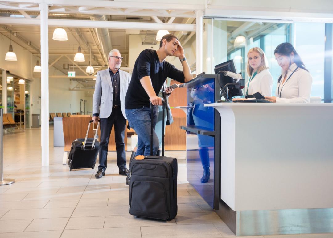Frustrated passenger getting bumped from his flight at airline check-in counter.