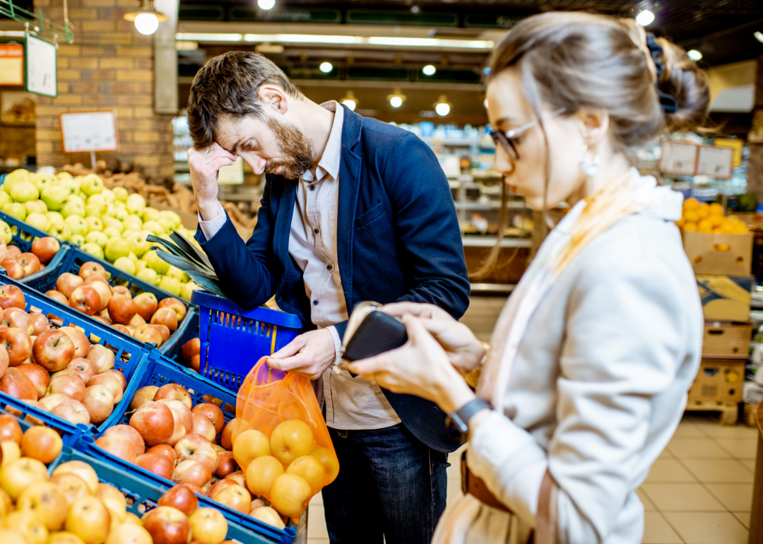 A concerned looking couple looking at fruit in a supermarket
