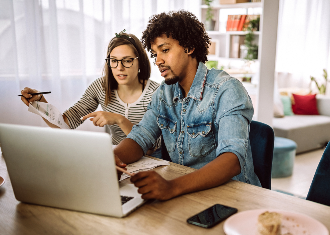 A couple considers their finances on a laptop.
