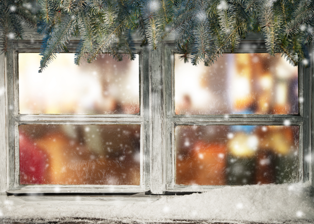 Pine needles hang above a window looking inside a house.