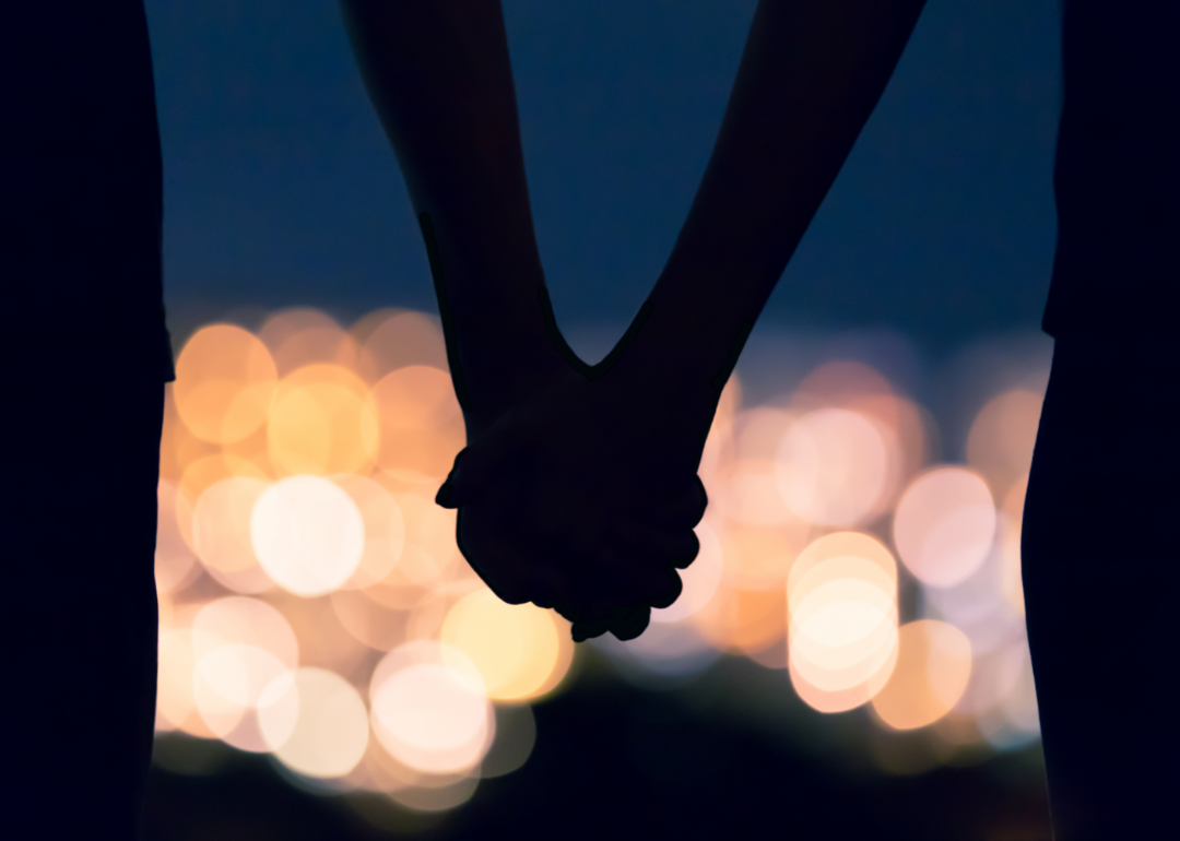 Two hands held in silhouette before a sea of lights.