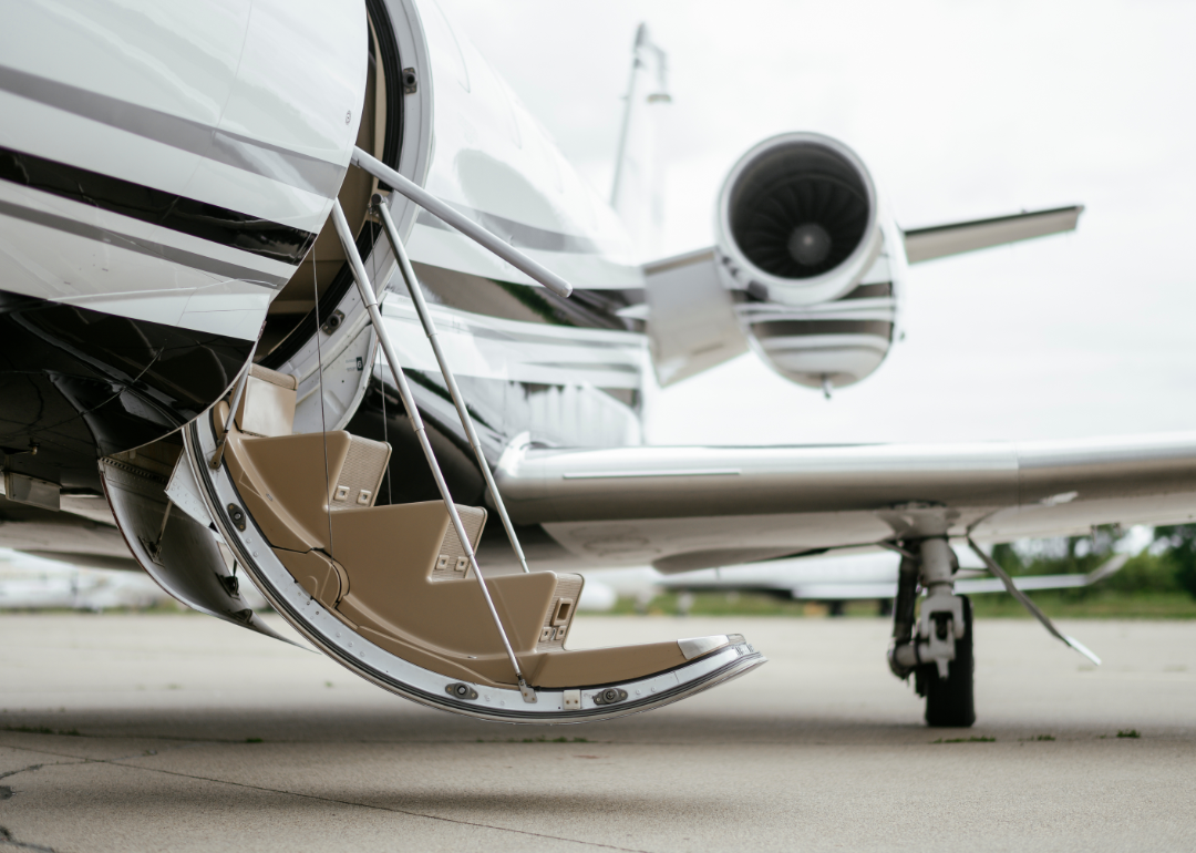 A private jet sits on a runway ready for boarding.