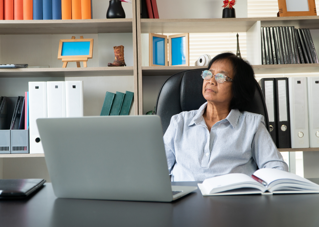 A woman at her laptop looks pensively out the window .