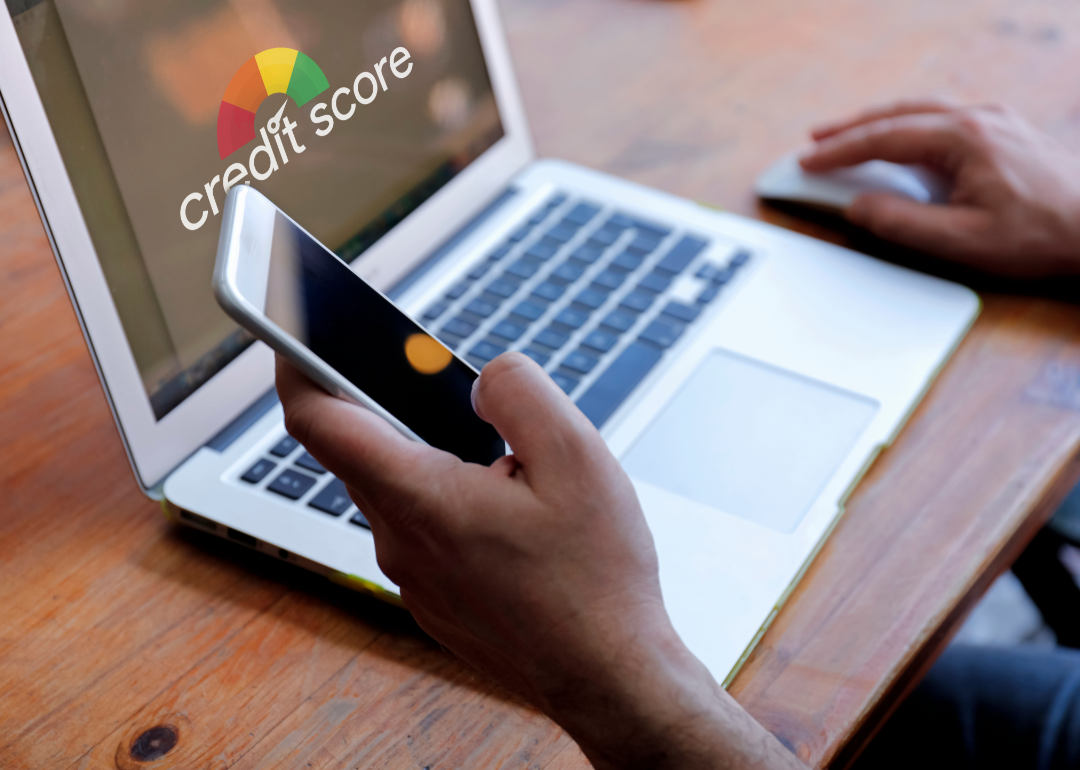 Two hands operating a laptop and smartphone.