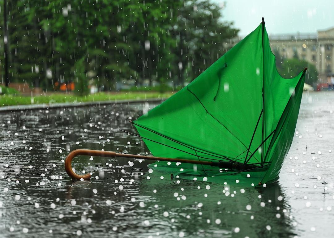 Broken green umbrella on the ground on a rainy day with hail.