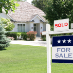 A photo of a home with a for sale sign in the front yard.