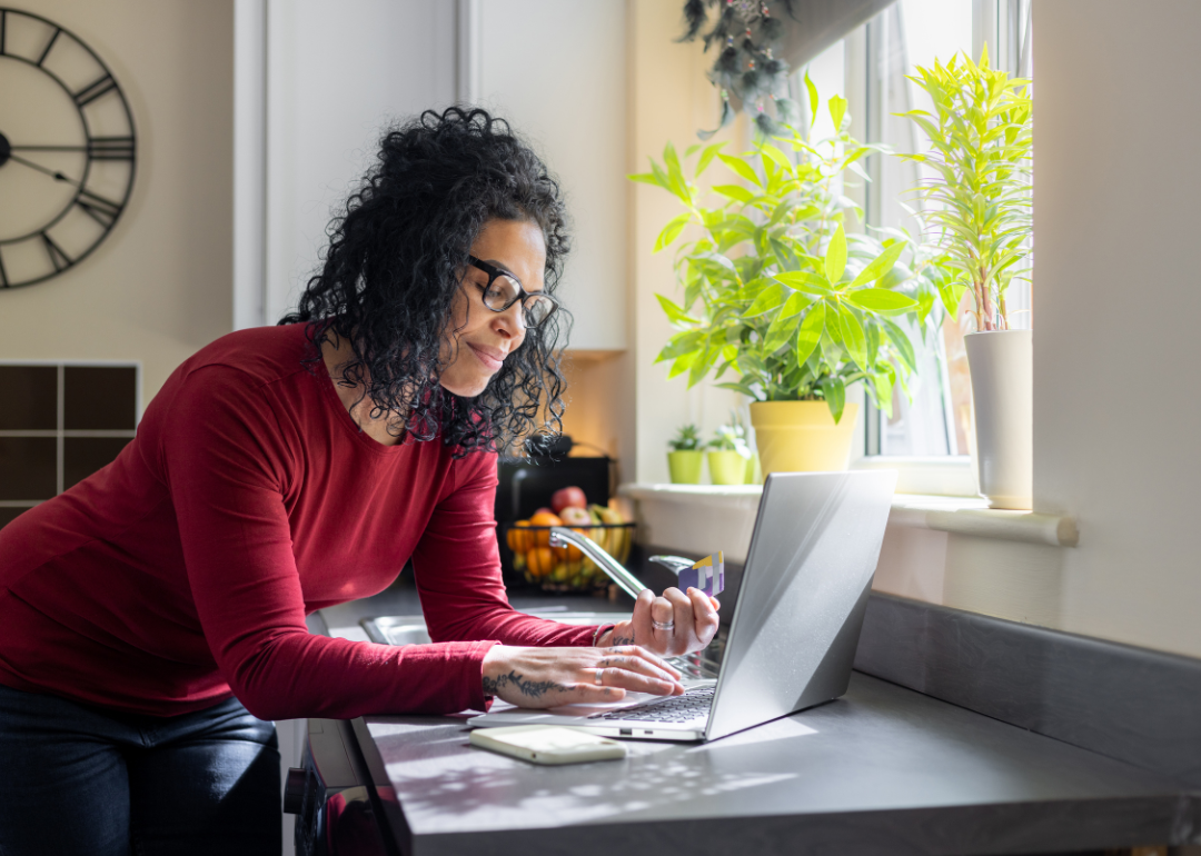 A woman looks at her laptop in her kitchen.