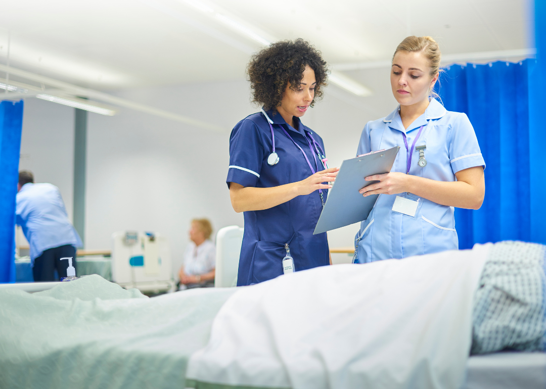 A nurse explains a chart to a student nurse in a hospital setting.