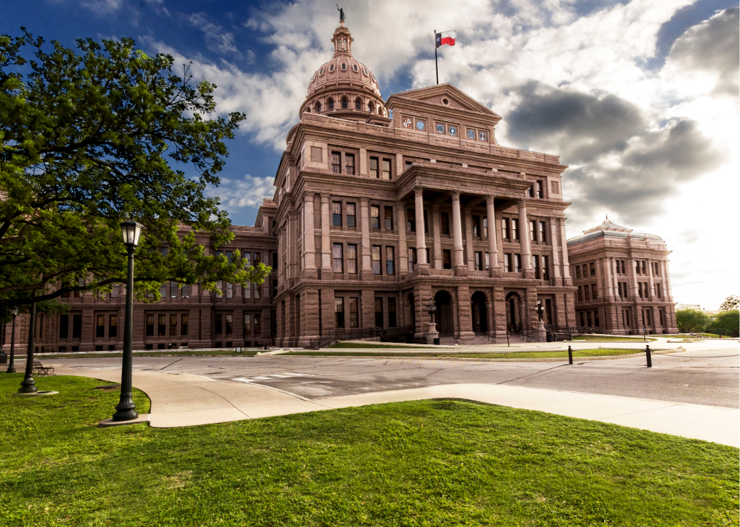A view of the Texas state capitol under dark clouds.