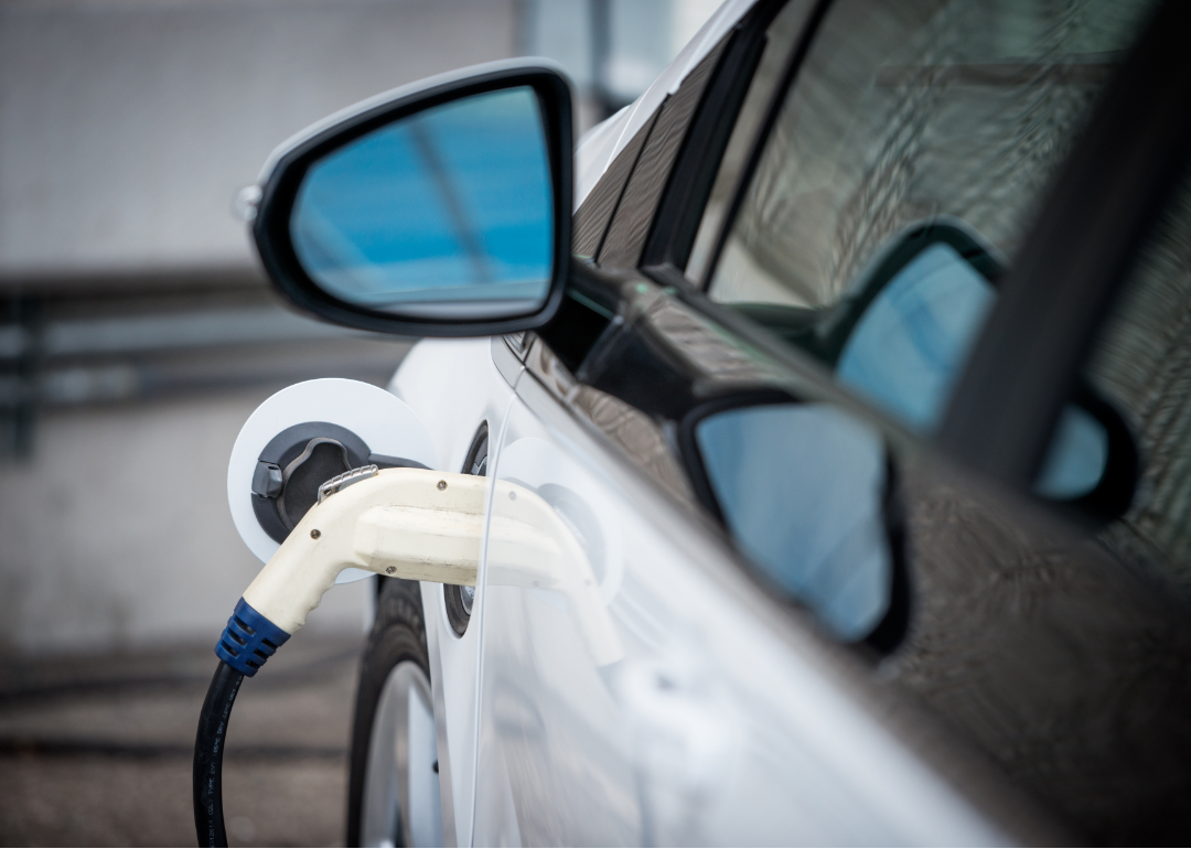 A white electric vehicle charging up at a charging station.