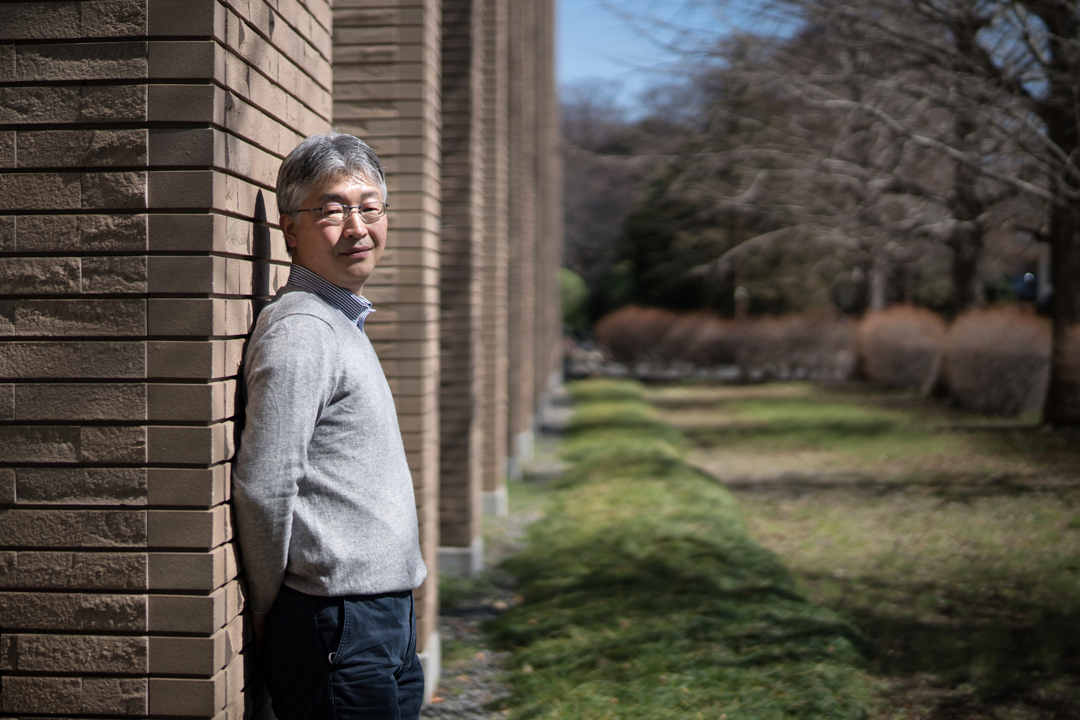 A man stands leaning against the wall of a building.
