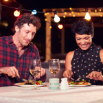 A couple enjoying a rooftop meal at night.