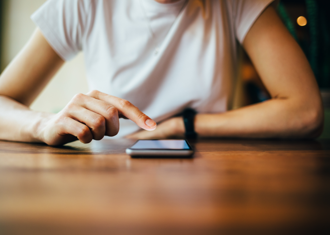 Person sitting at a table using a smartphone.