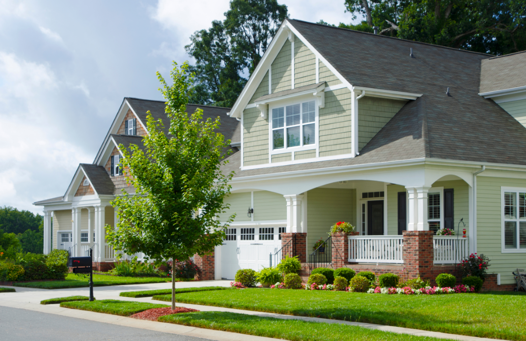 A pair of two-story houses in suburban neighborhood on a partly cloudy day.