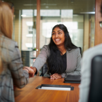 A woman smiling and shaking hands at a job interview