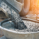 Close-up of concrete mixer truck pouring concrete into large basin.