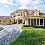 Exterior of a large home with a stucco roof and long paved drive