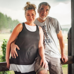 A Gen X couple stand together on the porch of a home