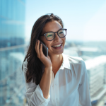 A smiling young woman in glasses talks on a smartphone