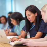 Group of nursing students sit at desk in front of a computer.