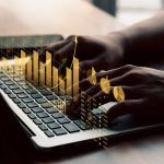person typing on computer with concept of financial graphs displayed