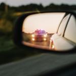 car sideview mirror of police lights approaching