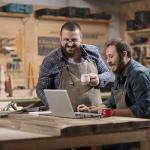 two men in a woodworking shop have a meeting with computer