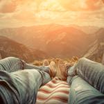 view from the trunk of a car of a sunset, legs of two people laying side-by-side visible 